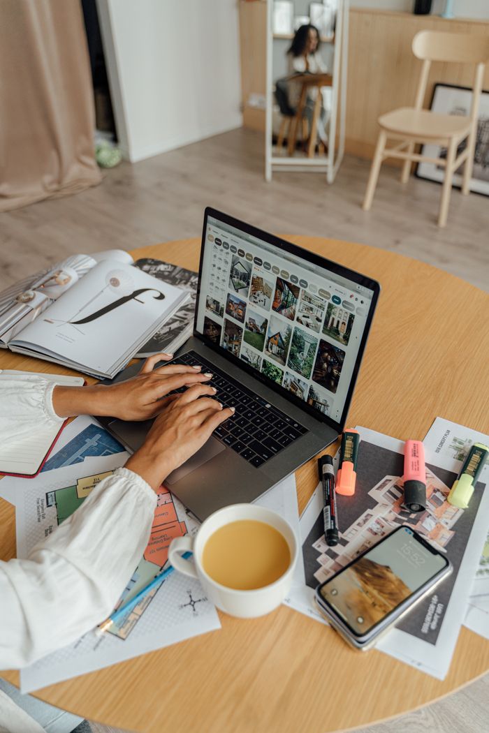 our-story A person working from home with a laptop, coffee, and magazines on a wooden table, showcasing a freelancing lifestyle.